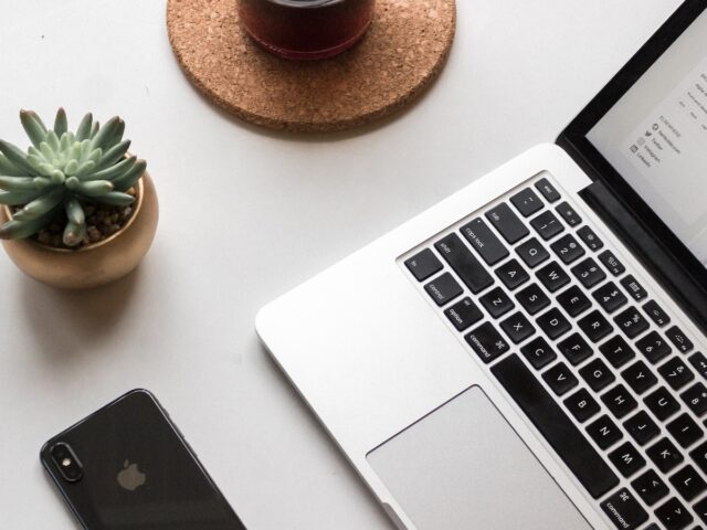 space gray iPhone X beside turned on laptop beside coffee and succulent plant